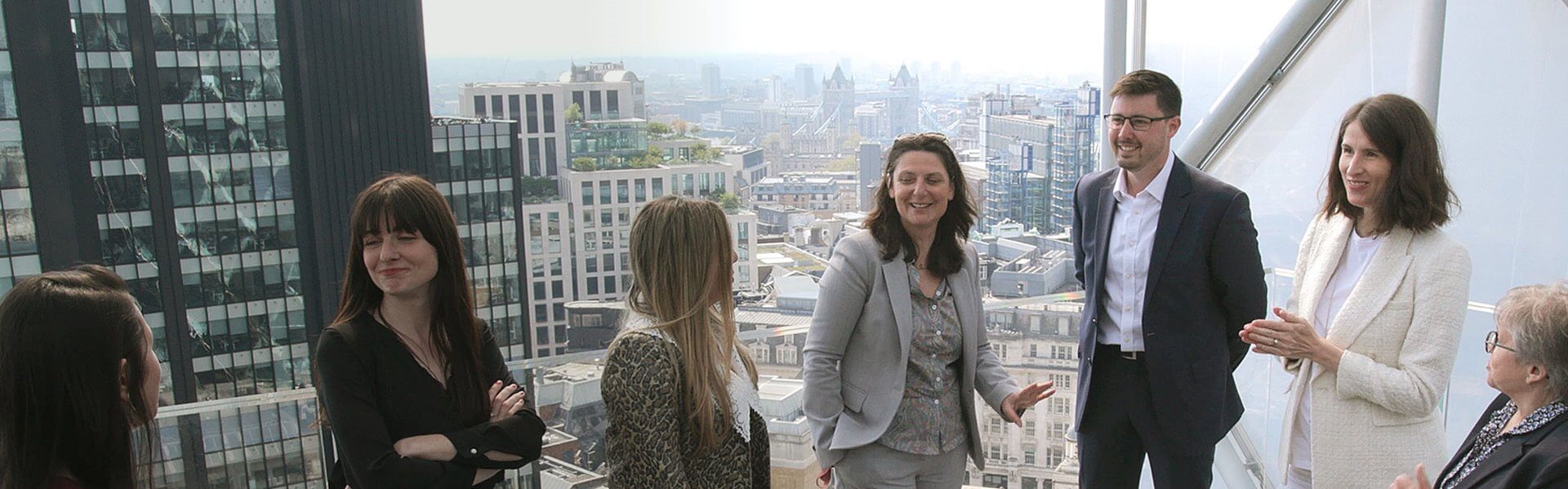 Image of some of the French Group team on the London office balcony, with views of London skyline behind