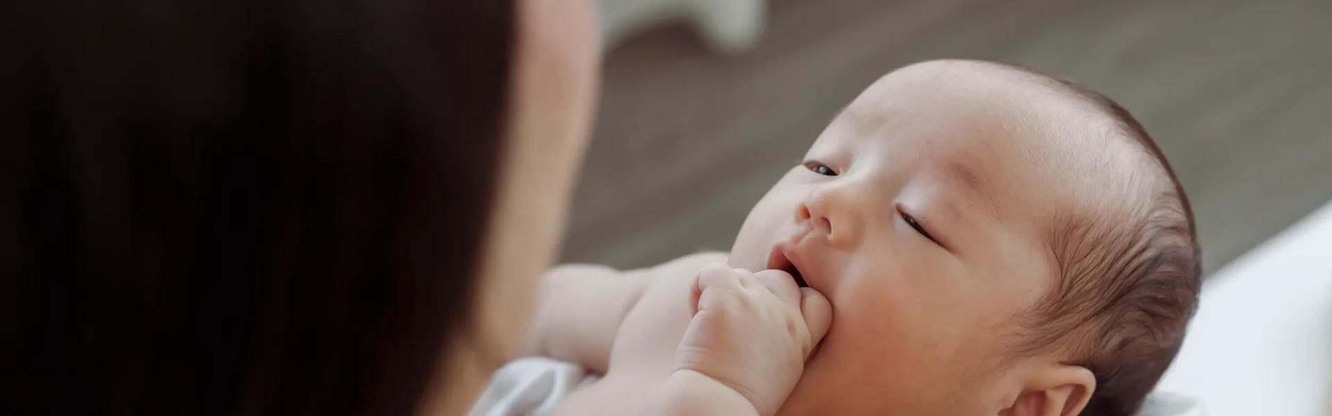 A woman holds a newborn baby wrapped in a yellow blanket.